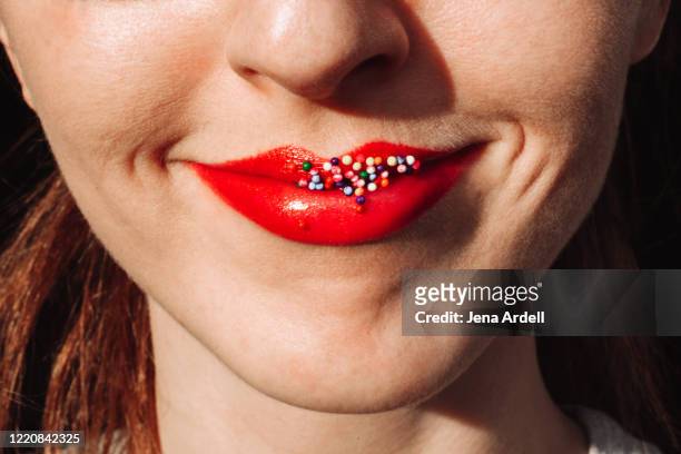 closeup woman smiling with red lipstick, sprinkles on mouth, sprinkles on lips - rossetto foto e immagini stock