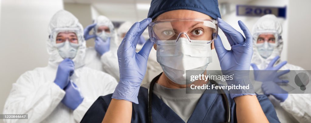 Team of Female and Male Doctors or Nurses Wearing Personal Protective Equiment In Hospital Hallway