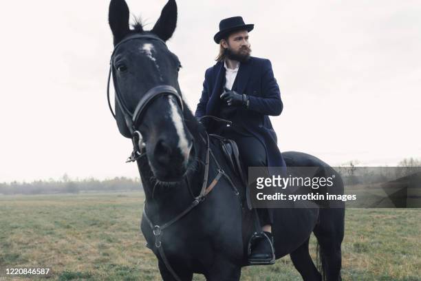 stylish boy training on horse among field. - 1910 stock-fotos und bilder