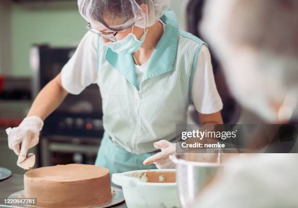 caterer preparando alimentos en cocina comercial - máscara quirúrgica fotografías e imágenes de stock