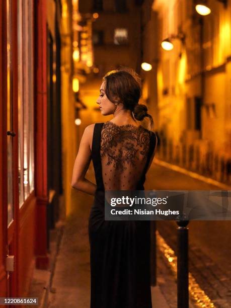 woman in street looking into window at night in paris, france - street light post stock pictures, royalty-free photos & images