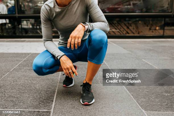 break from the workout: runner in blue tights squating on the street - maillot de sport stockfoto's en -beelden