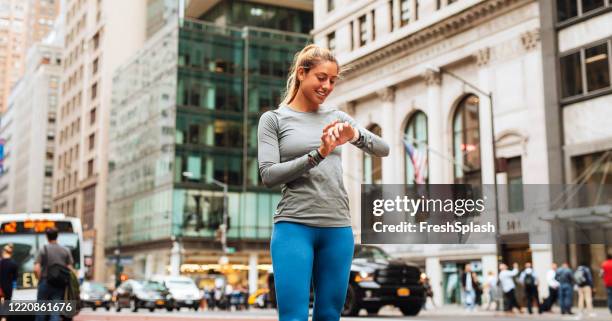 mooie fit blonde vrouw die impuls van haar smartwatch tijdens haar looppas van de ochtend neemt - maillot de sport stockfoto's en -beelden