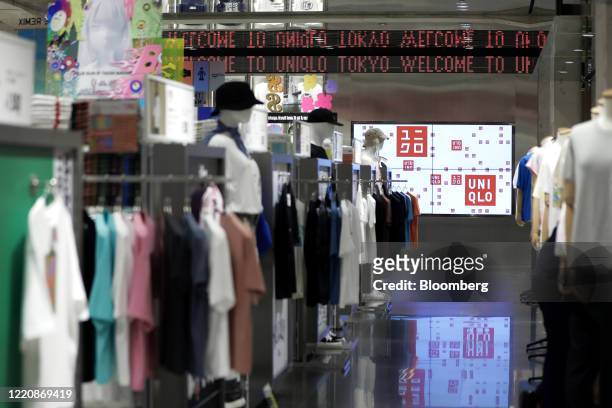 The Uniqlo logo is displayed on screens near clothing during a media tour of the Uniqlo Tokyo flagship store, operated by Fast Retailing Co., in the...