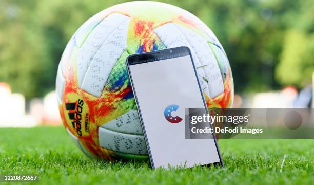 Smartphone is leaning against a play ball with the open start page of the Corona Warn app on the screen prior to the 3. Liga match between FC...