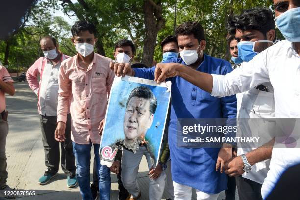 Members of National Students' Union of India hold a partially-burnt poster of Chinese President Xi Jinping during an anti-China demonstration in...