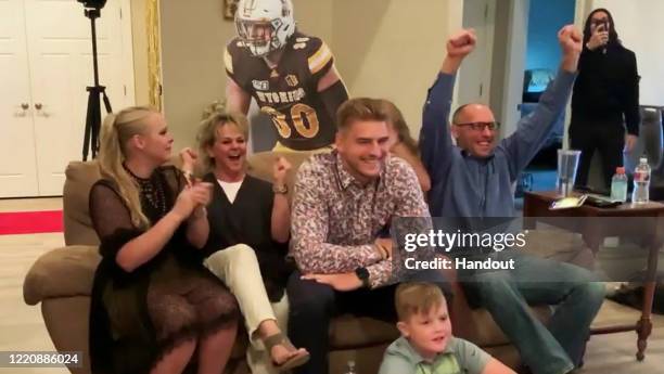 In this still image from video provided by the NFL, Logan Wilson, center, reacts after being selected by the Cincinnati Bengals during the third...