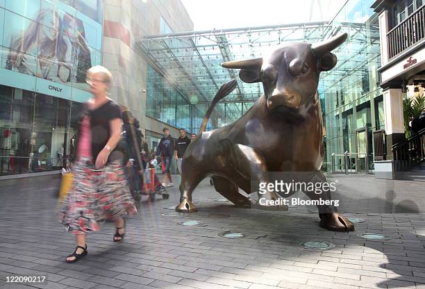 Pedestrian passes a statue of a bull outside the Bullring shopping center, operated by Hammerson Plc, in Birmingham, U.K. On Thursday, Aug. 25, 2011....