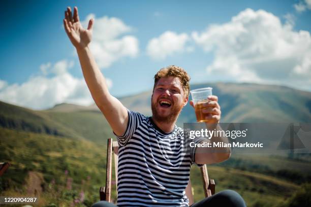 hij wandelaar rust op de top van de berg met een biertje - man sipping beer smiling stockfoto's en -beelden