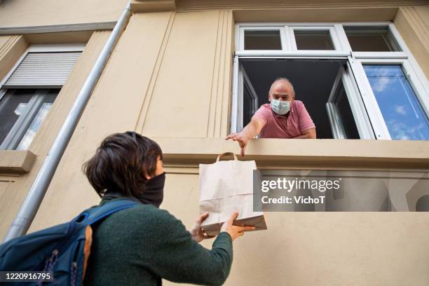 jonge volwassene die een zak met het winkelen aan zijn vader door het venster geeft - quarantaine stockfoto's en -beelden