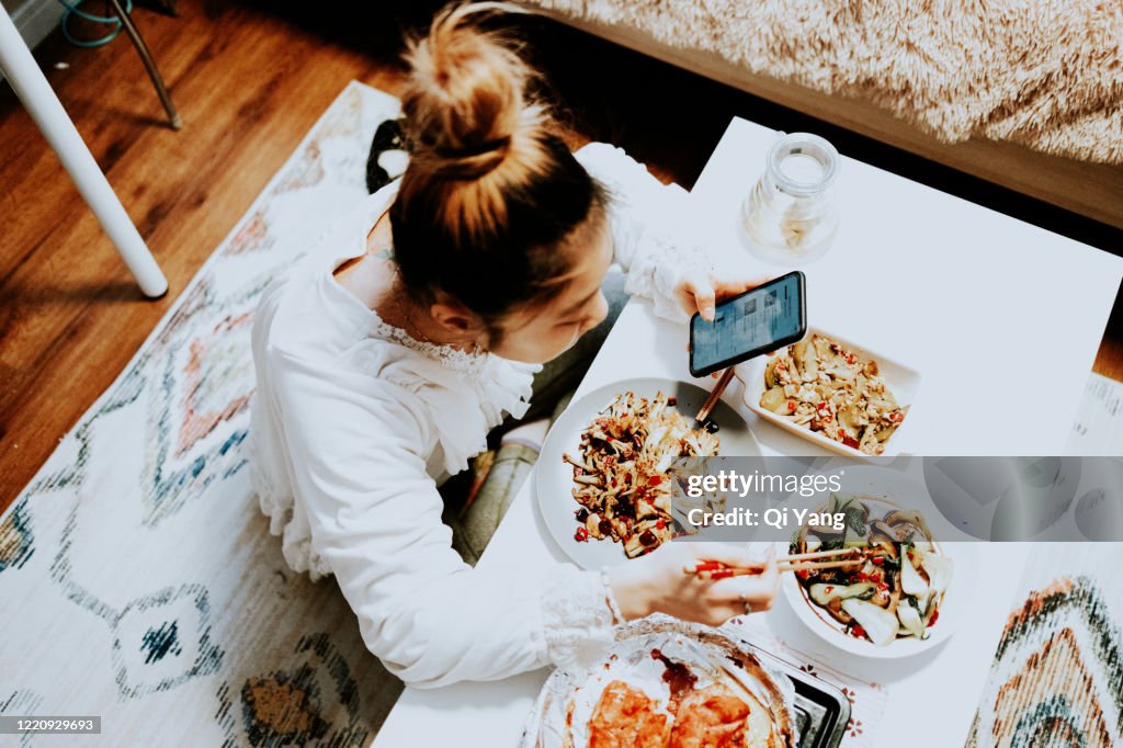 Young Asian woman enjoying Chinese food in bedroom