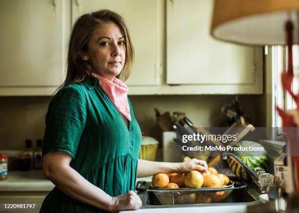portrait of woman wearing bandana in kitchen - homemaker stock-fotos und bilder