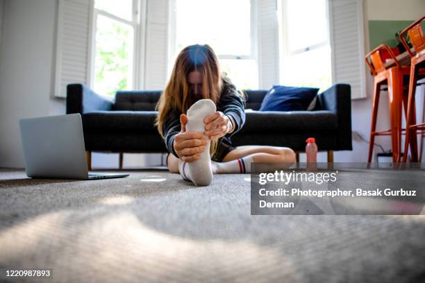 a woman exercising at home, watching exercise videos from ler laptop. - home workout stock pictures, royalty-free photos & images