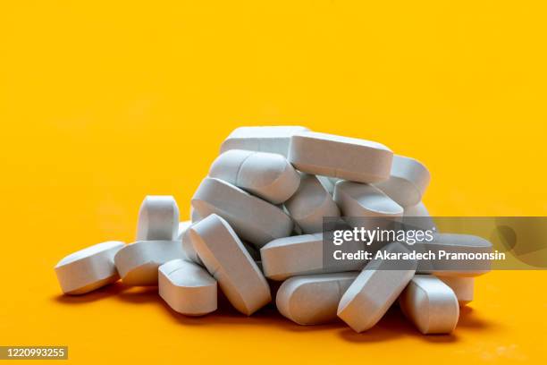 pills white pigment for on a yellow background - prescription drugs dangers stock pictures, royalty-free photos & images