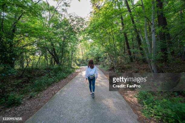 a young female hiking in a forest park - adult girl single park photos et images de collection