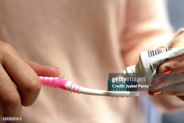 woman putting toothpaste on toothbrush - 歯みがき粉 ストックフォトと画像