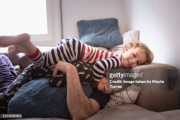 boy layiing on top of brother in the sofa - angelica hale fotografías e imágenes de stock