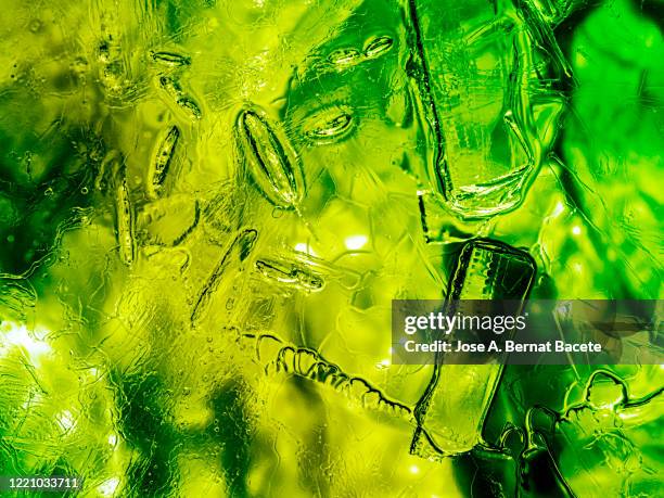 full frame of the textures formed of a block of cracked ice on a green color background. - soft drink stock-fotos und bilder