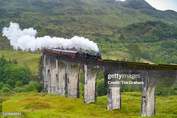 The Jacobite' locomotive steam train on West Highland Rail crosses famous Glenfinnan Viaduct tourist spot in the Highlands of Scotland.