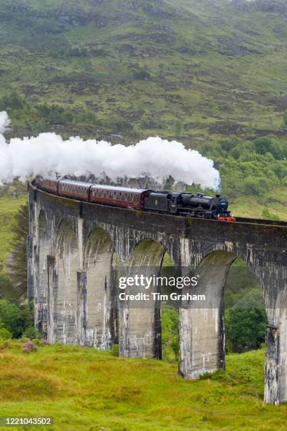 The Jacobite' locomotive steam train on West Highland Rail crosses famous Glenfinnan Viaduct tourist spot in the Highlands of Scotland.