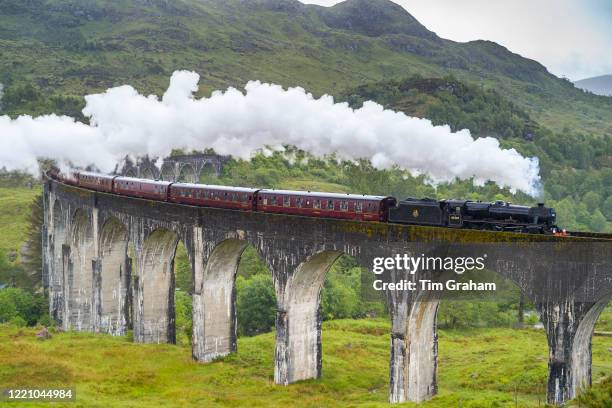 The Jacobite' locomotive steam train on West Highland Rail crosses famous Glenfinnan Viaduct tourist spot in the Highlands of Scotland.