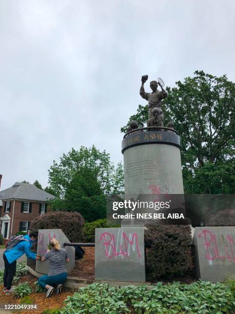 Richmond residents clean up the statue of Arthur Ashe on Monument Avenue in Richmond, Virginia, on June 17 after it was tagged with graffiti - A...