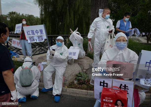 Chinese epidemic control workers wear protective suits as they wait to assist people who have had contact with the Xinfadi Wholesale Market or...