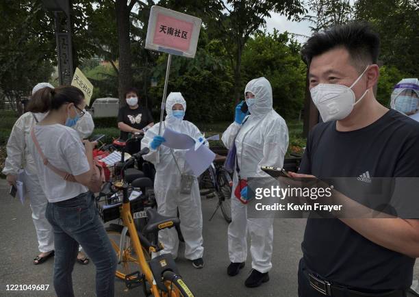 Chinese epidemic control workers wear protective suits as they assist people who have had contact with the Xinfadi Wholesale Market or someone who...