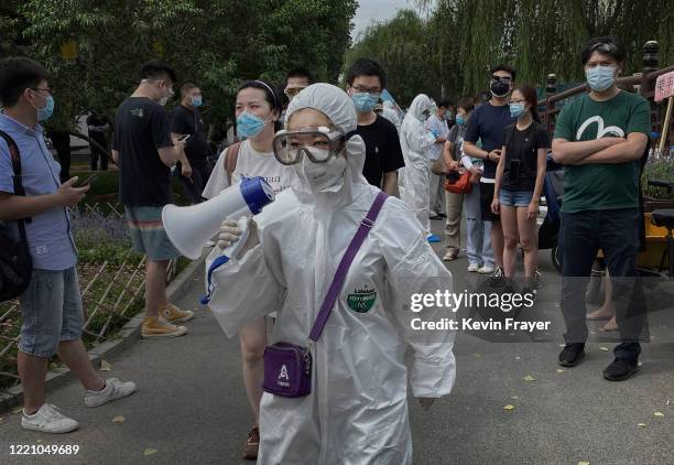 Chinese epidemic control worker wears a protective suit as she directs people who have had contact with the Xinfadi Wholesale Market or someone who...