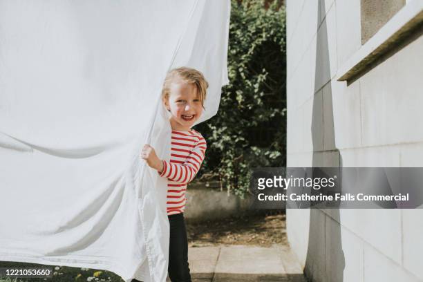 peeking out from behind washing - white laundry foto e immagini stock