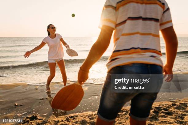 friends playing beach tennis - racket stock pictures, royalty-free photos & images