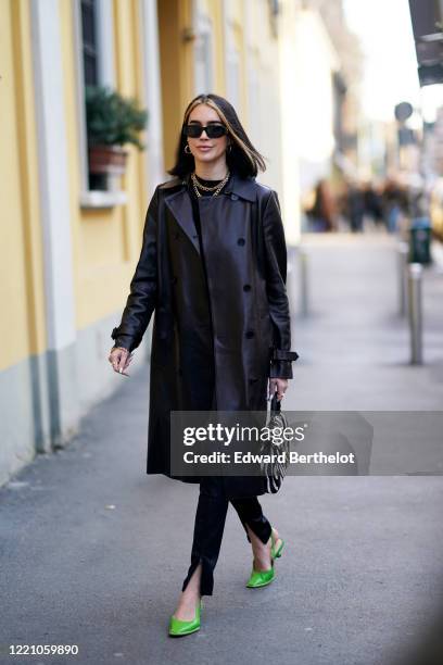 Brittany Xavier wears sunglasses, a black leather long coat, a golden necklace, a black and white zebra print bag, pants, green pointy shoes, outside...
