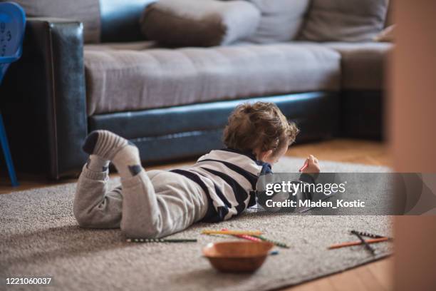 kleinkind junge auf einem boden liegen und malbücher - auf dem bauch liegen stock-fotos und bilder