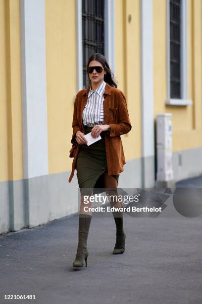 Guest wears sunglasses, a white striped shirt, a brown GZ suede jacket, a green/khaki skirt, high heel pointy boots, outside Tod's, during Milan...