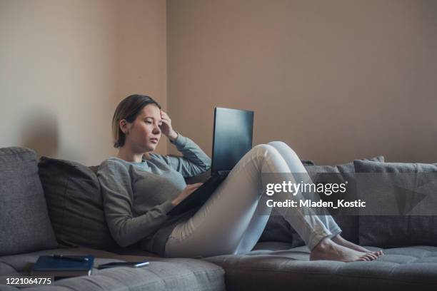 woman lying down on sofa and desperately looking for a job on her laptop - job interview nervous stock pictures, royalty-free photos & images