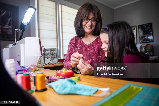 grandma showing little girl her sewing masks - cloth face mask stock pictures, royalty-free photos & images