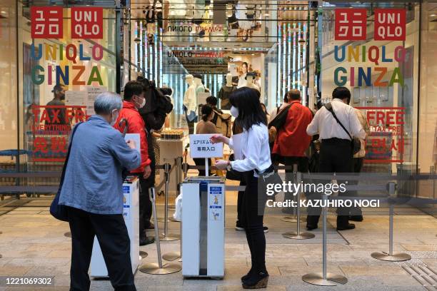 Customers wait in a queue outside a Uniqlo store selling face masks made by Japan's Fast Retailing Co. In Tokyo's Ginza shopping district on June 19,...