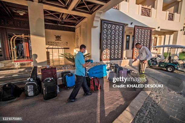 Man disinfects suitcases in the Steigenberger hotel in the Red Sea Egyptian resort of Hurghada on June 18, 2020. - Egypt will reopen its airports on...