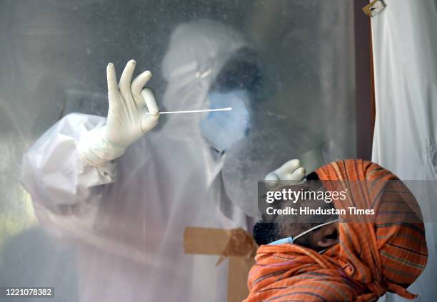Health worker collects a swab sample from a man to test for coronavirus infection, at a COVID-19 testing lab in Patel Nagar, on June 18, 2020 in New...