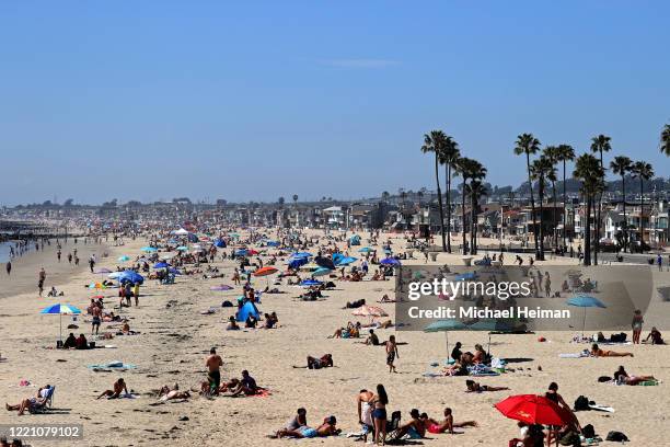 People are seen gathering on the beach north of Newport Beach Pier on April 25, 2020 in Newport Beach, California. Southern California is expecting...