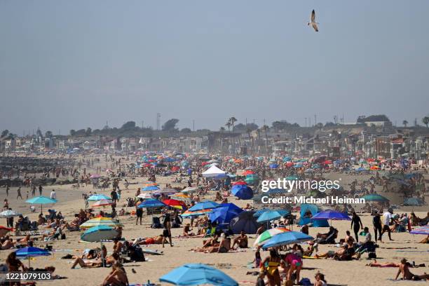 People are seen gathering on the beach north of Newport Beach Pier on April 25, 2020 in Newport Beach, California. Southern California is expecting...