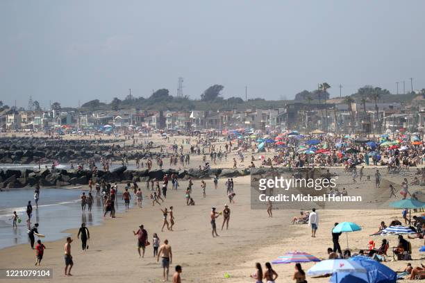 People are seen gathering on the beach north of Newport Beach Pier on April 25, 2020 in Newport Beach, California. Southern California is expecting...