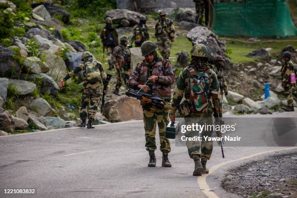 Indian Border Security Force soldiers patrol a highway as Indian army convoy passes through on a highway leading towards Leh, bordering China, on...