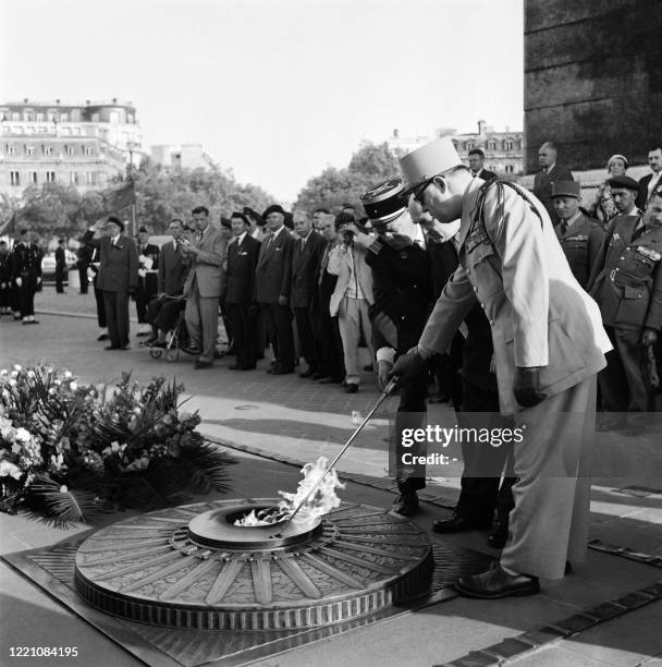 General lights the flame of the grave of the unkown soldier during the annual Bastille Day military parade in Paris on July 14, 1958.