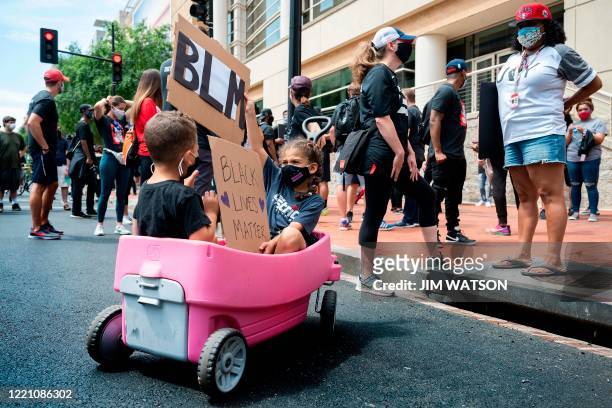 Two children sit in a wagon with Black Lives Matter signs as they wait for a Juneteenth march and rally to begin in Washington, DC, on June 19, 2020....