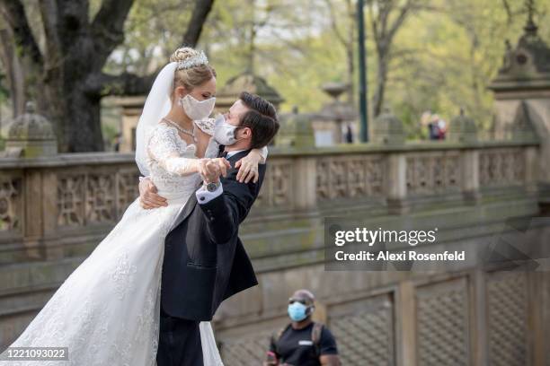 Couple wearing protective masks take wedding photos in Central Park as temperatures rose amid the coronavirus pandemic on April 25, 2020 in New York...