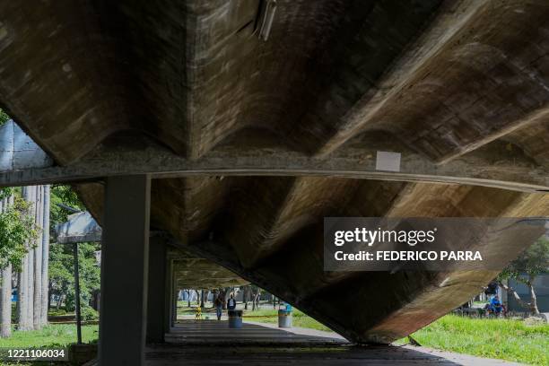 People walk near a collapsed roof at the Central University of Venezuela in Caracas, on June 18, 2020. - Declared a world heritage site by UNESCO, an...