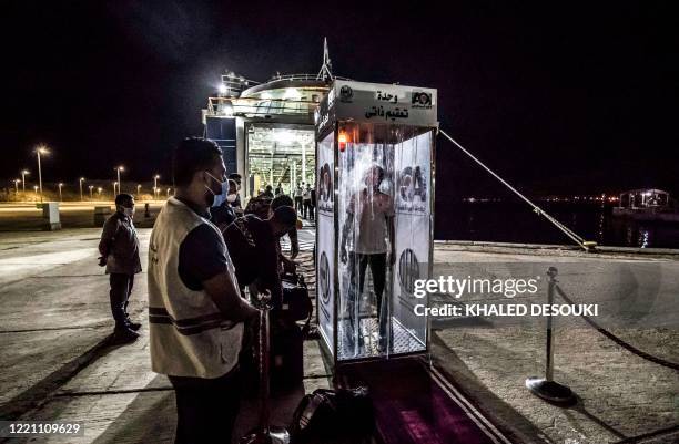 Traveller passes through an automatic disinfection booth upon arrival by the Queen Nefertiti ferry from Hurghada at the seaport of Egypt's Sinai...