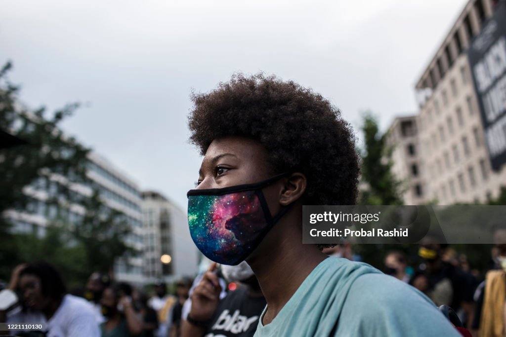 A young woman wearing a protective mask at a gathering to...