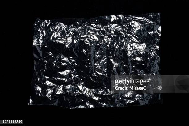 transparent shiny plastic foil on black - candy wrapper stock-fotos und bilder